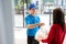 Food Delivery man wearing mask handling plastic bags shopping online from supermarket to female client