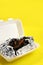 Food delivery in plastic packaging to your home. Mussels in sauce in foil and plastic container on a yellow background