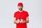 Food delivery, quarantine, stay home and order online concept. Smiling courier in red cap and t-shirt bring coffee to