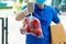 Food delivery service man in blue uniform wearing protection face mask holding fresh red apple fruit waiting for customer