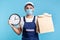 Food delivery, shipping on time! Portrait of handyman in uniform, gloves holding clock