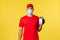 Food delivery, tracking orders, covid-19 and self-quarantine concept. Young courier in red uniform and medical mask