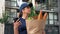 Food delivery woman courier uses smartphone holds paper bag looking address