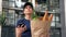 Food delivery woman courier uses smartphone holds paper bag looking address