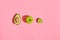 Food design. Composition of fresh fruits, avocado green apple and half of cutted avocado on pink coral background