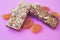 Food Dessert Bar with muesli cereals and chocolate with dried apricot on pink background paper isolate