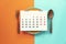 Food diary or food daily calendar, dish spoon and fork on the color table background