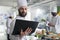 Food industry worker having laptop, following gourmet dish recipe on screen stirring ingredients in pan