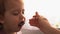 food, nutrition, childhood concepts - medium shot Mom feeding infant baby with rubber spoon. Cute hungry child dressed