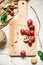 Food photo: branch of red grapes and walnuts on wooden board, on light background, top view. Sloppy still life.