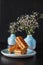 Food photo three delicious wafers with white filling in the pale blue bowl vases with baby`s breath on black dark background clos