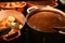 Food photography image of large pans or pots filled with hot gravy and golden color crispy roast potatoes on a dark surface