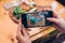 Food photography for social networks. Close-up image of female hands holding phone with food on screen taking picture of