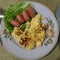 Food in a plate, top view. Omelette and few small sausages