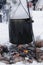 Food preparation in huge black bowl on bonfire in winter time