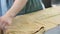 Food production. A man working with a large piece of rolled dough.