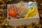 Food set: banana, eggs, nuts, pumkin, coffee and oils in a wooden box against the background of autumn yellow foliage.