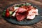 Food tray with delicious salami, pieces of sliced ham, sausage, tomatoes, salad and vegetable - Meat platter with selection