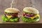 food. Two hamburger with cutlet grilled, lettuce, tomato, cheese, cucumber on a light wooden background