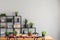 Food on wooden table and plants on black shelves in grey dining room interior with copy space