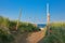 Foodpath surrounded by high grass and barrier with red rope leading to beach on island Texel in the Netherlands