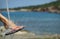 Foot in beach slides under water spray, water drops splashing around. Blue sea and coastline. Free space on right side