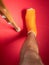 Foot with broken toe bone in orange fiberglass cast pink background. Injured fractured swollen male leg. Patient body