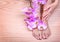 Foot care. Pedicure with pink orchid flowers on wo