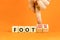 Foot or footloose symbol. Businessman turns wooden cubes and changes word Foot bad to Footloose. Beautiful orange table orange