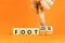 Foot or footloose symbol. Businessman turns wooden cubes and changes word Foot bad to Footloose. Beautiful orange table orange