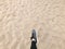 The foot in the gray boot shoe makes a step against the background of a natural loose yellow golden beautiful warm beach sand