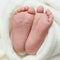 Foot and little fingers of a newborn baby on a white wrap background closeup