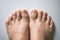 The foot and long nail toes on white concrete background.