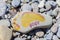 Foot painted with yellow watercolor paints on beach stone as a foot on the sea