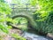 Foot path stony bridge over stream at autumnal garden park