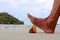 Foot stepping on broken glass bottle on the beach.