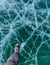 A foot of tourist standing on the cracks surface of frozen lake Baikal in the winter season of Siberia, Russia