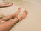 foot of woman sitting on moist sand beach and have little water