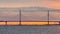 footage of cable-stayed bridge at sunset, car traffic on the highway over water, magic reflection on water, water