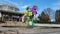 Footage of a colorful origami bouquet of flowers in the center of a pool reflecting off the water with two women walking