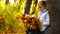 Footage girl sitting on a tree and holding autumn leaves