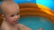 Footage infant boy swimming in pool and play with fish toy.