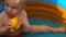 Footage infant boy swimming in pool and play with fish toy.