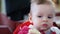 Footage little boy sitting on children\'s chair and eats bread.