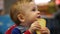 Footage little boy sitting on children\'s chair and eats bread.