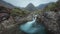 Footage of a morning view of a river with a waterfall and a mountain range covered in clouds