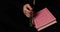 Footage of a Muslim woman holding a pink Quran and praying on her tasbeeh, the prayer beads