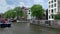 Footage of people riding boats on Amstel river, historical and traditional buildings, trees in Amsterdam.