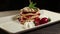 Footage of a portion of pancakes decorated with strawberries on a plate lying on a table, the shot is rotating on a table