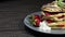 Footage of a portion of pancakes decorated with strawberries on a plate, the shot is rotating on a wooden table
